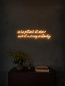 A living room wall in deep charcoal plaster with a single custom LED neon installation