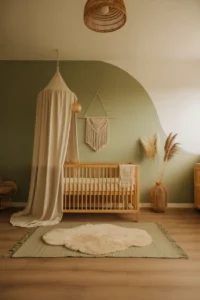 a boho girl nursery with matte sage green walls and one white accent wall