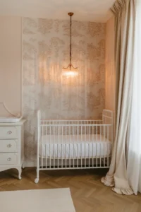 a vintage French-inspired girl nursery with a soft blush and white toile wallpaper accent wall