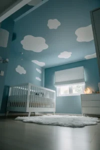 boy nursery painted in matte dusty blue with soft white cloud shapes
