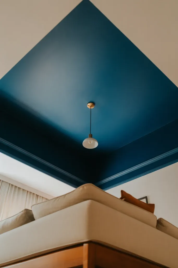 deep navy painted ceiling with a simple brass pendant light hanging center