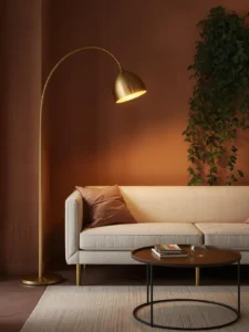 living room corner with a tall brushed brass arched floor lamp