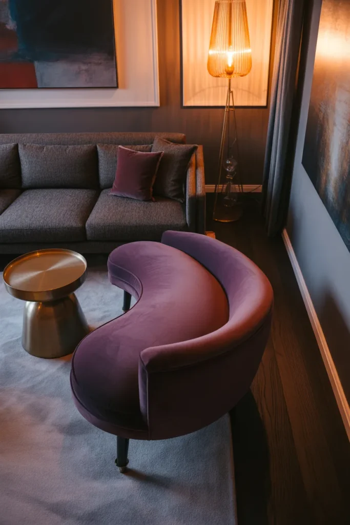 a curved velvet chaise lounge in deep plum positioned at the end of a gray sofa