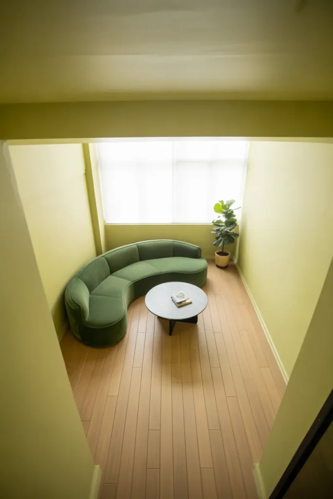 a small rectangular living room with a curved sage green velvet sofa against one wall